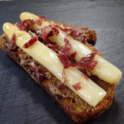 Spanish tapa. White asparagus toast with black olive spread and Jamón Ibérico de Bellota